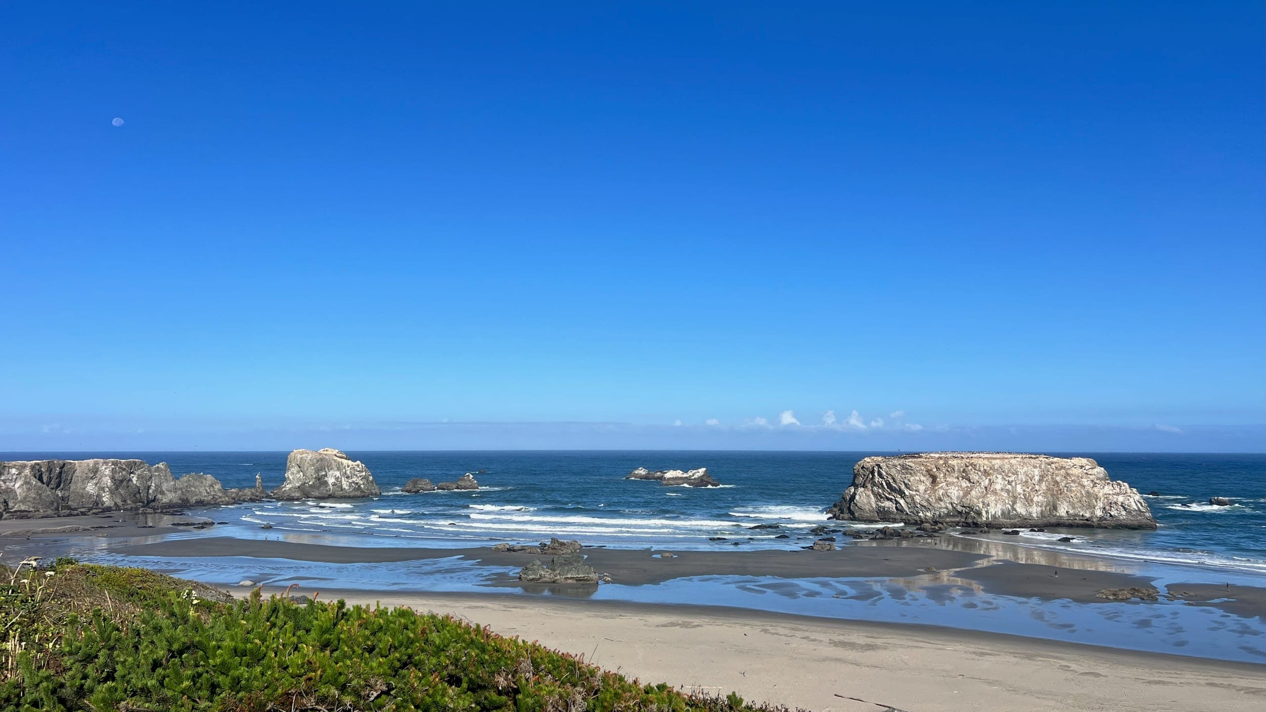 The end of Eighth Street overlooking a wide sandy beach and rock formations in the Pacific Ocean.